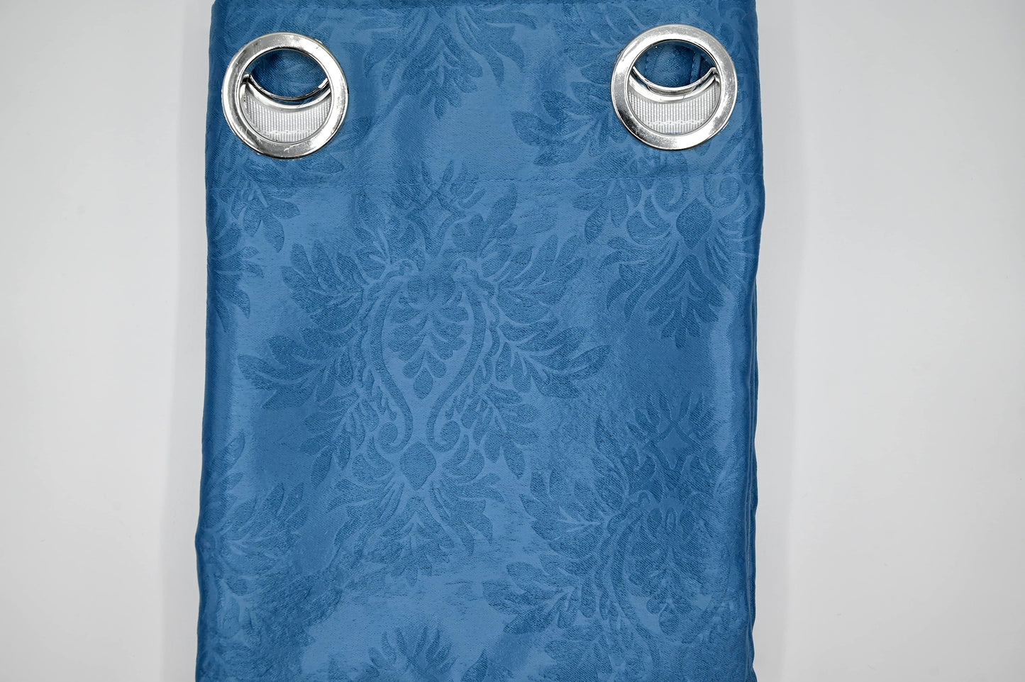 Blue curtain with floral pattern and metallic eyelets on a white background