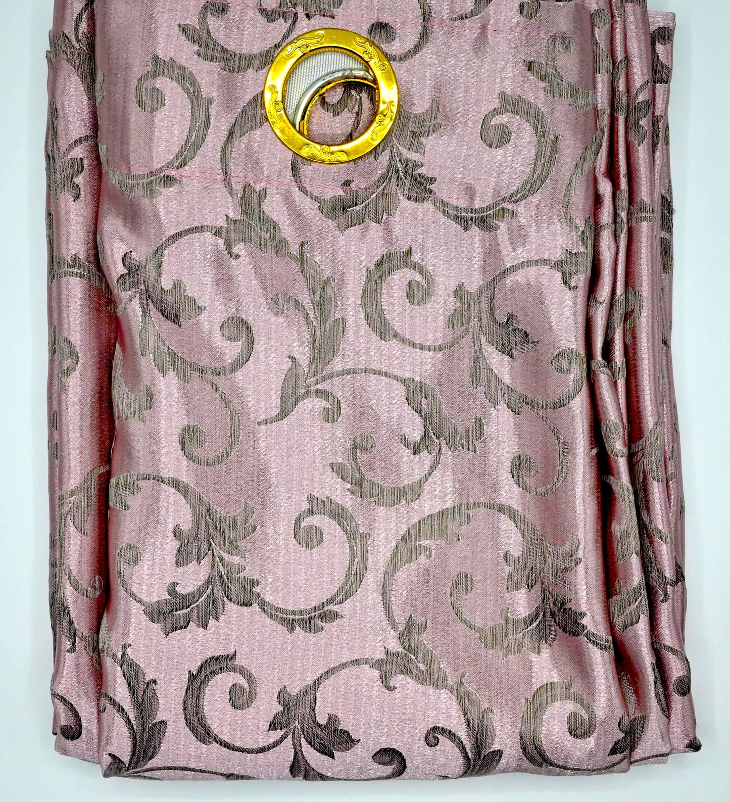 Pink fabric with intricate gold patterns and a gold ring on a white background