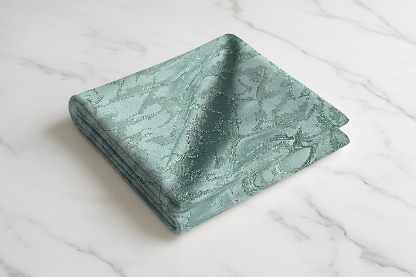 Sage green print curtain fabric folded on white marble surface with textured pattern