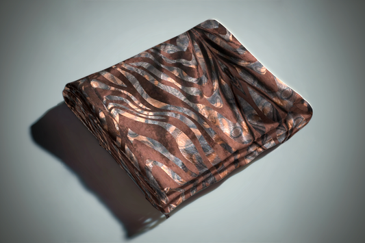 Brown and copper zebra print curtain fabric with metallic animal pattern folded on grey surface