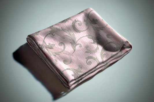 Pink damask curtain fabric with ornate pattern and metallic finish folded on surface