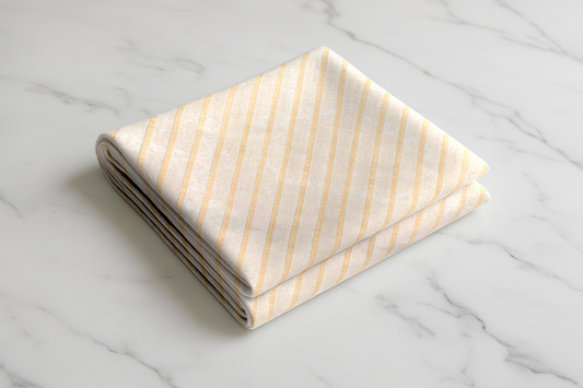 Folded beige curtain with thin gold vertical stripes, ready-made with metal eyelets for easy hanging