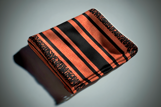 Orange and black striped curtain fabric with geometric pattern and textured weave folded on surface