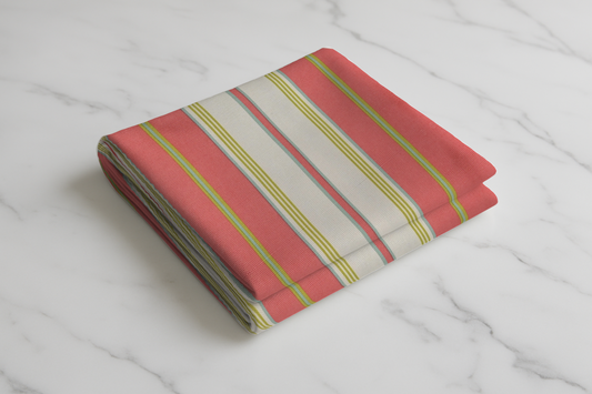 Coral red and cream striped curtain fabric with yellow and green accent lines folded on marble surface
