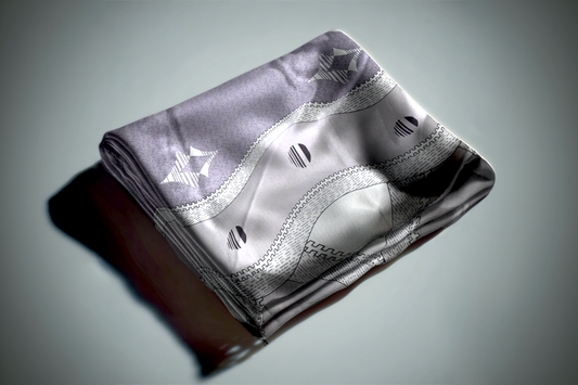 Silver and gray geometric curtain fabric with abstract wave pattern and metallic finish folded on grey surface