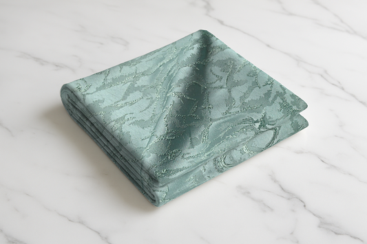 Sage green print curtain fabric folded on white marble surface with textured pattern